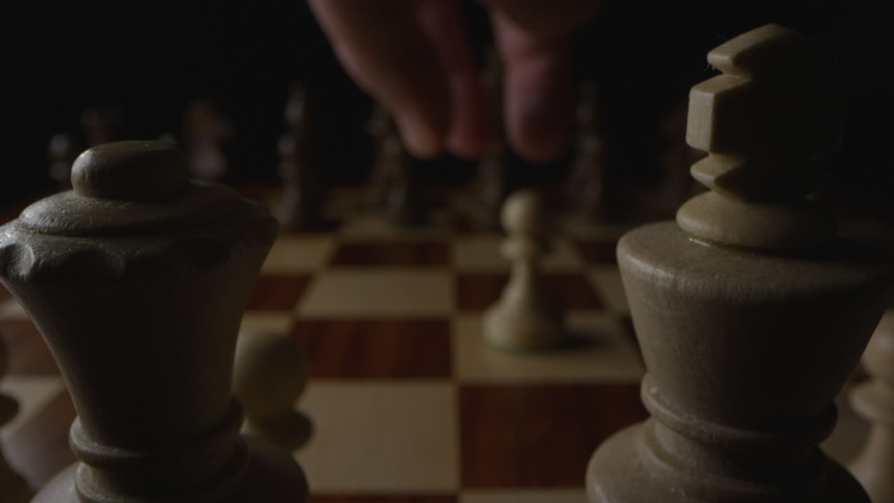 la mano del jugador de ajedrez toma una pieza de peón y la mueve hacia atrás dos espacios ilegalmente