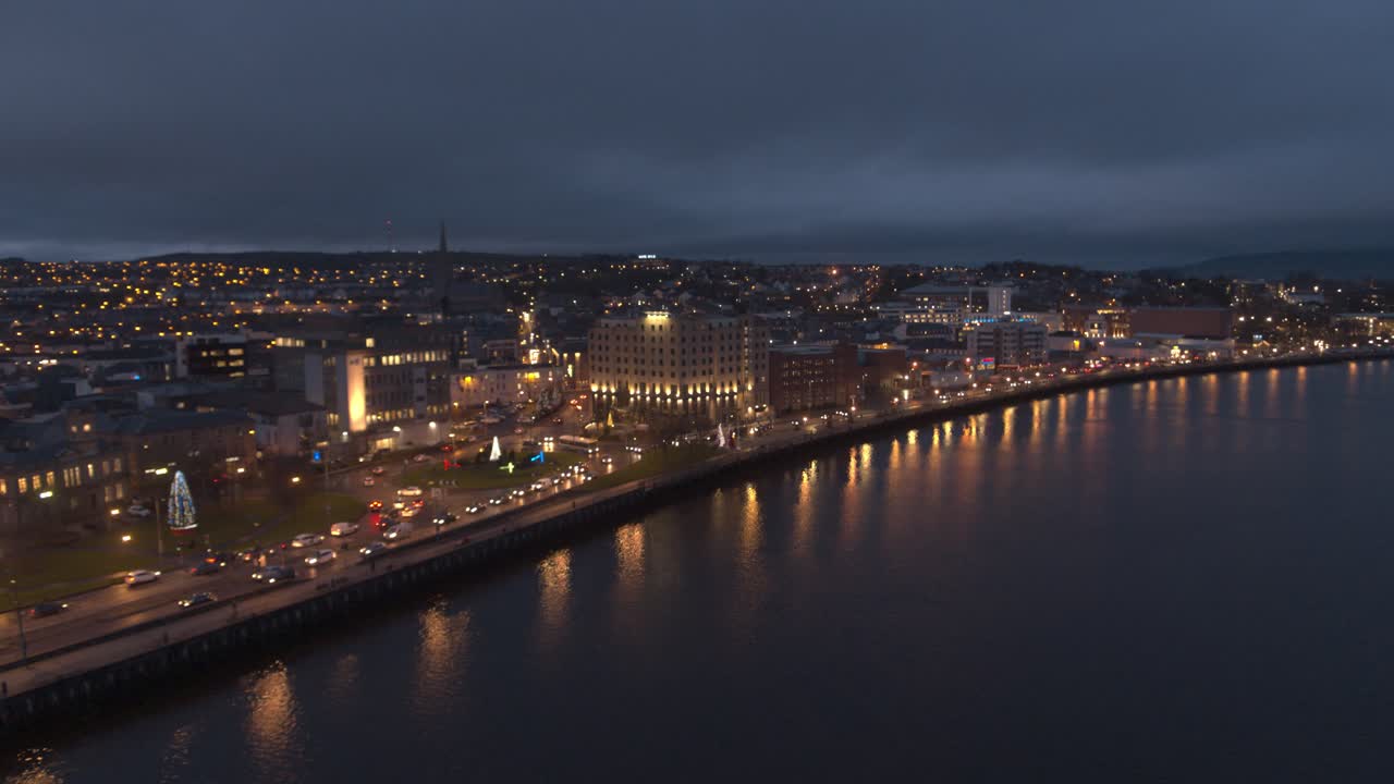 Londonderry - Derry - Stroke City - Legenderry night time aerial footage in UHD. Cityscapes of the Peace Bridge, The Foyle River, Guildhall, St Columb's Cathedral, Shipquay Street, Craigavon Bridge