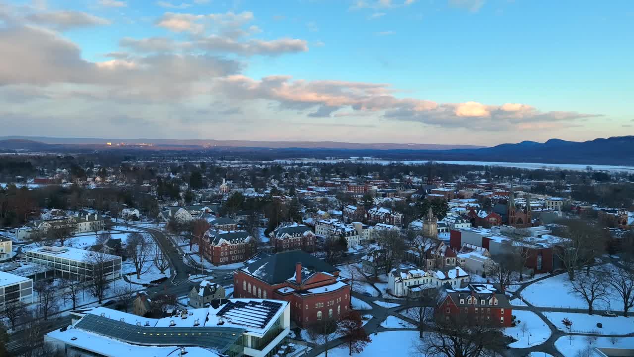 Beautiful drone footage capturing the snowy town of Northampton, showcasing historic architecture, tree-lined streets, and a stunning winter landscape under a clear blue sky.