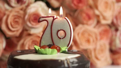 large bouquet of pink roses and birthday cake with burning candle number 70