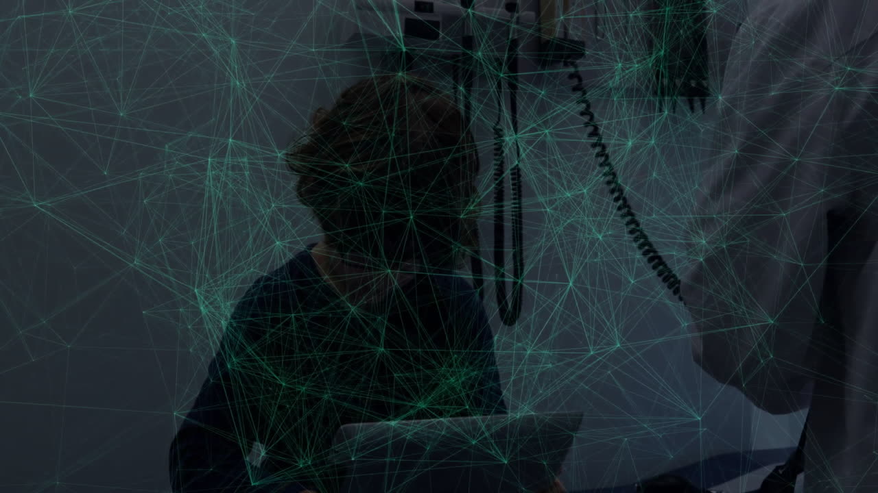 Male doctor using stethoscope on seated boy holding tablet in clinic, showing network overlay