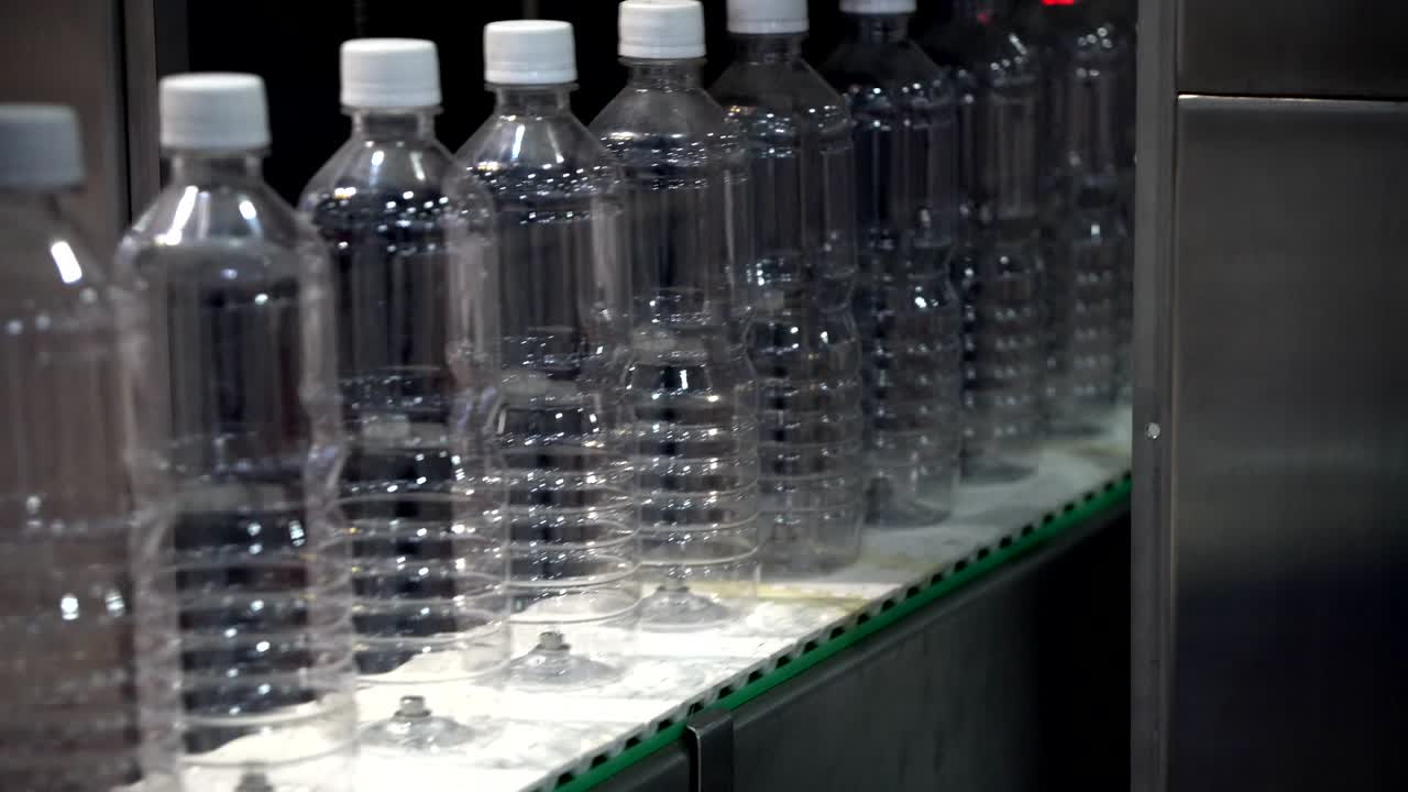 las nuevas botellas de plástico en la cinta transportadora en la fábrica de bebidas.