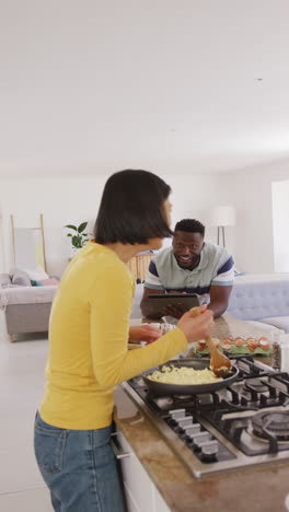 vertical video of happy diverse couple preparing breakfast in kitchen