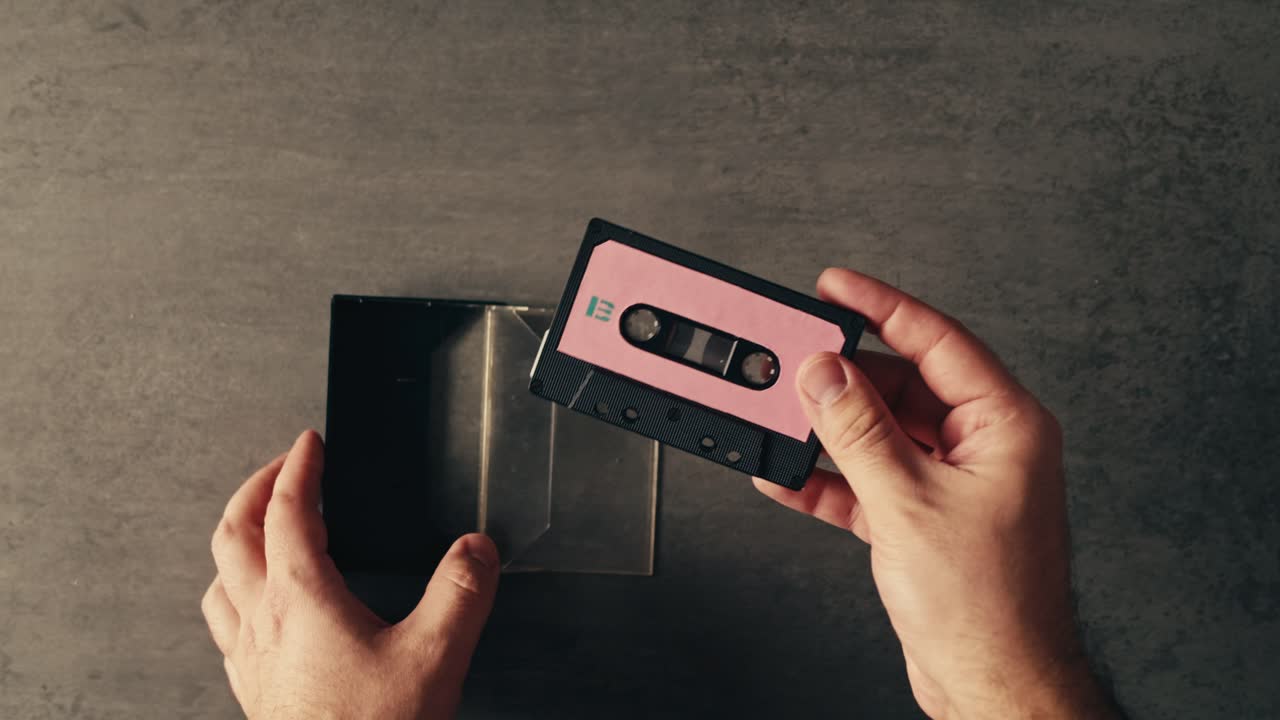 manos abriendo una caja de cinta de cassette