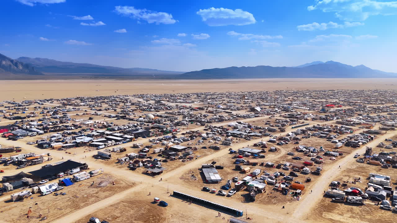 Drone panoramic view of the large Burning Man camp city stretching across the desert landscape