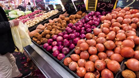 persona que selecciona verduras en el puesto del mercado