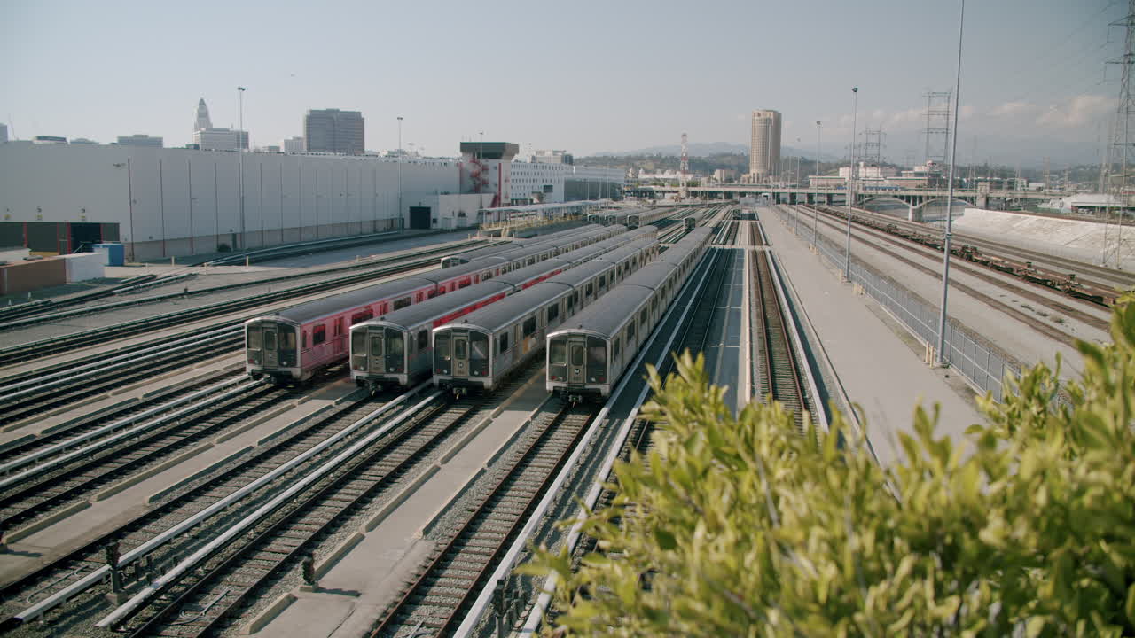 Subway trains parked in a rail yard with city buildings in the background