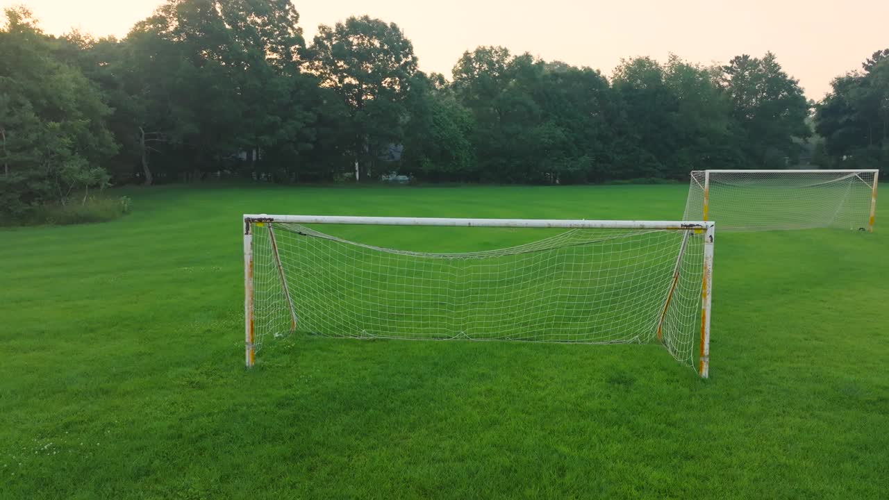 A soccer net sitting in an empty soccer practice field