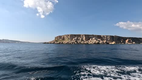 Overlooking-from-the-sea-towards-a-mostly-barren,-uninhabited-islet-of-Malta,-part-of-the-Maltese-Archipelago