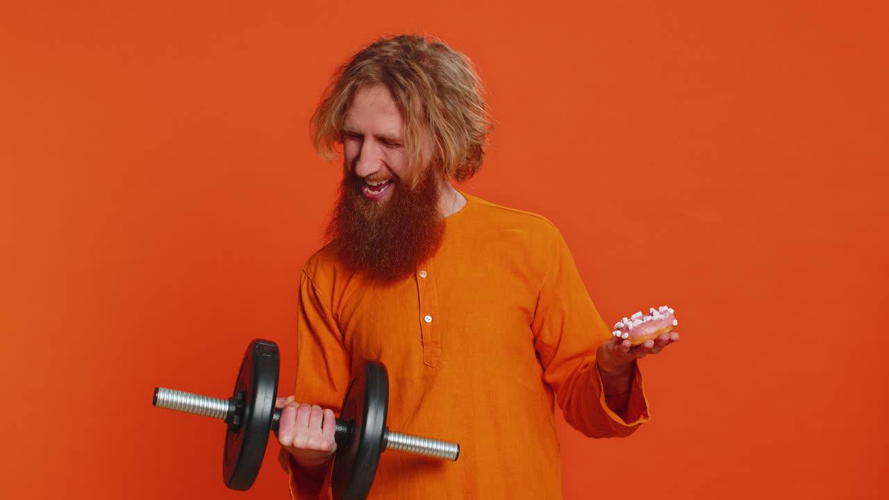 Mand holder håndvægt og sød donut og vælger mellem fitness, sport, kost, vitamin, ernæring eller junkfood