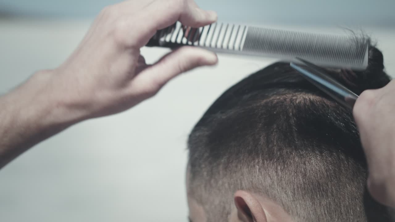 Taglio capelli uomo all'aperto. Acconciatura maschile. Taglio di capelli alla moda. Taglio capelli hipster