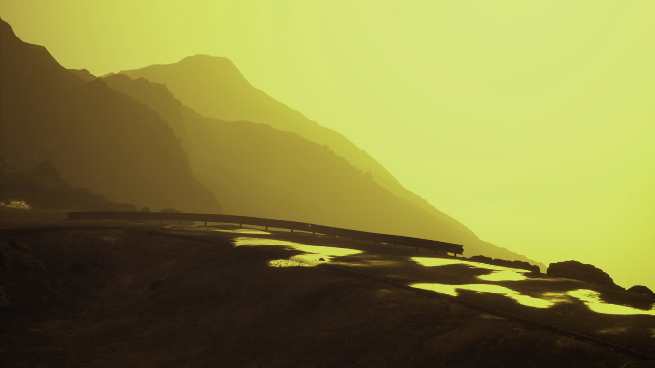 Majestic mountain road at sunset with golden hues and reflection on wet ground