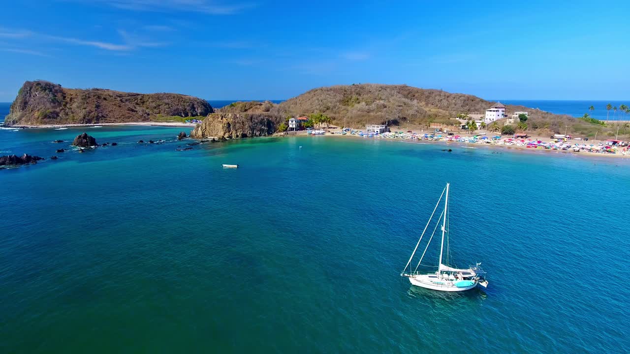 antena panorámica alrededor de un velero anclado cerca de islas rocosas con olas de surf