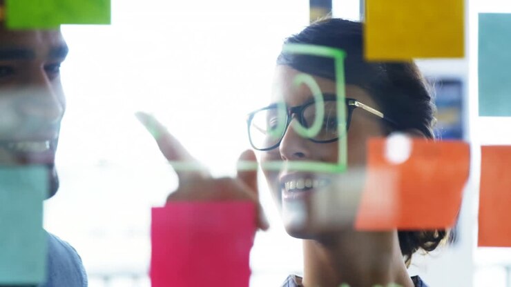 Executives discussing over sticky notes on glass wall