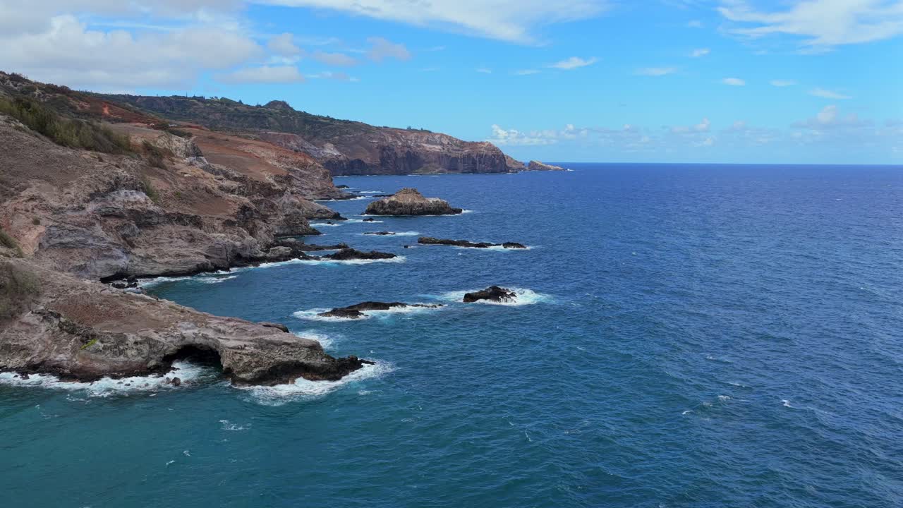 Drone pans across a rocky Hawaiian shore rarely seen by visitors, revealing epic cliff faces and turning to show the magnificent view of the island from the sea. 2 of sequence of 5
