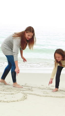 mother and daughter drawing on the sand