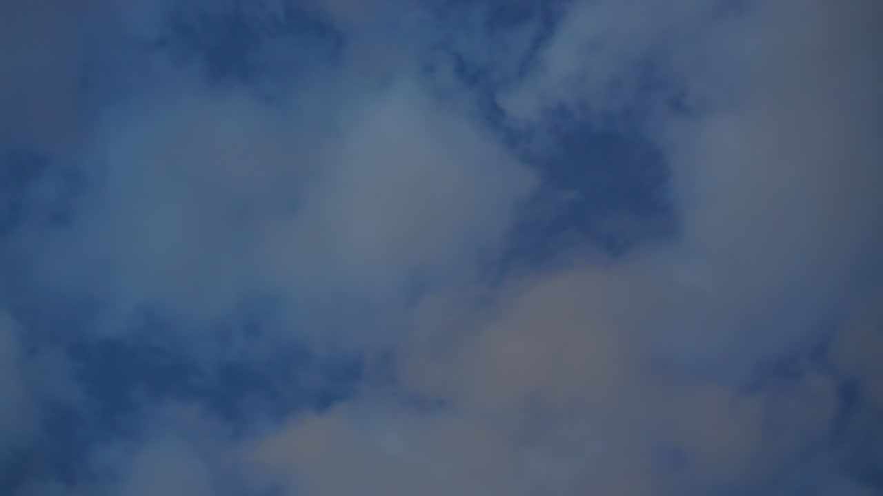 Rotational view of moody blue evening sky with scattered thick clouds moving gently creating dynamic atmospheric texture and soft dreamy background for nature, travel