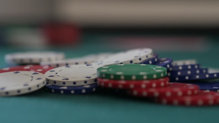 Primo piano di una pila di fiches da poker su un tavolo mentre ne vengono aggiunte altre durante la fase di scommessa.