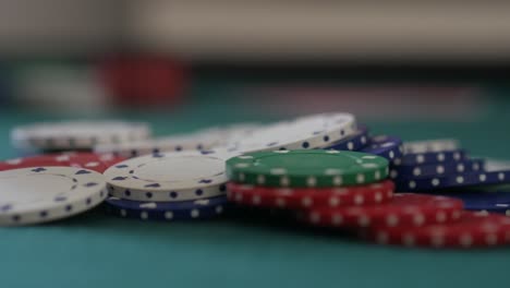 close-up of a pile of poker chips on a table as more are added to the pile as betting takes place