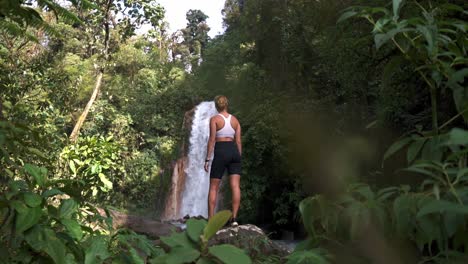 woman standing on a large rock with las gemelas waterfalls cascading behind them