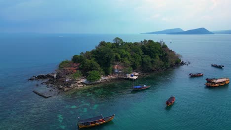 tourist boats surrounding a small tropical island in koh rong, cambodia, with crystal clear water and lush vegetation. perfect aerial view flight drone shot footage from above