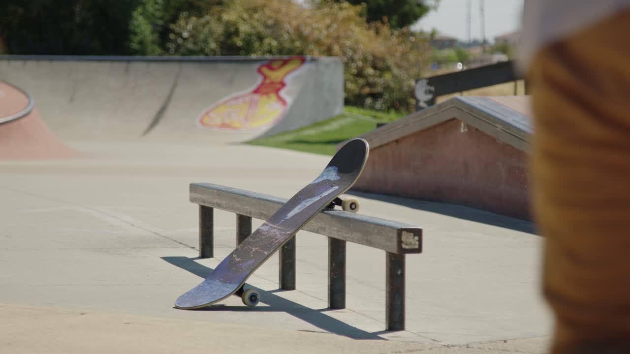 A skateboarder jogs up to grab their board resting on a rail, then quickly hops on and pushes away