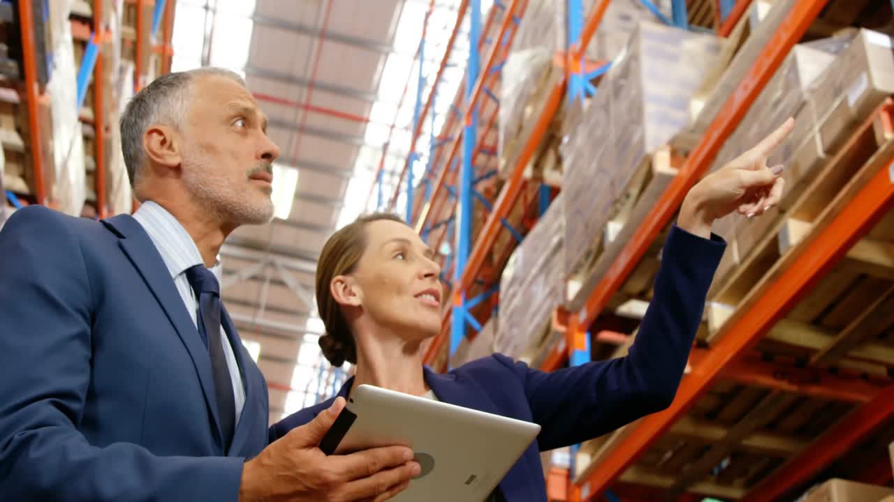 Responsabili della logistica che indicano gli scaffali e scorrono su un tablet mentre avviano una sovrapposizione di tracciamento animata