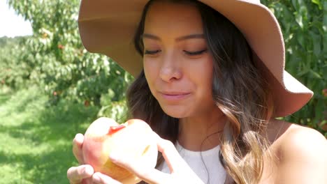 Woman-bites-into-a-juicy-peach,-just-picked-from-the-tree