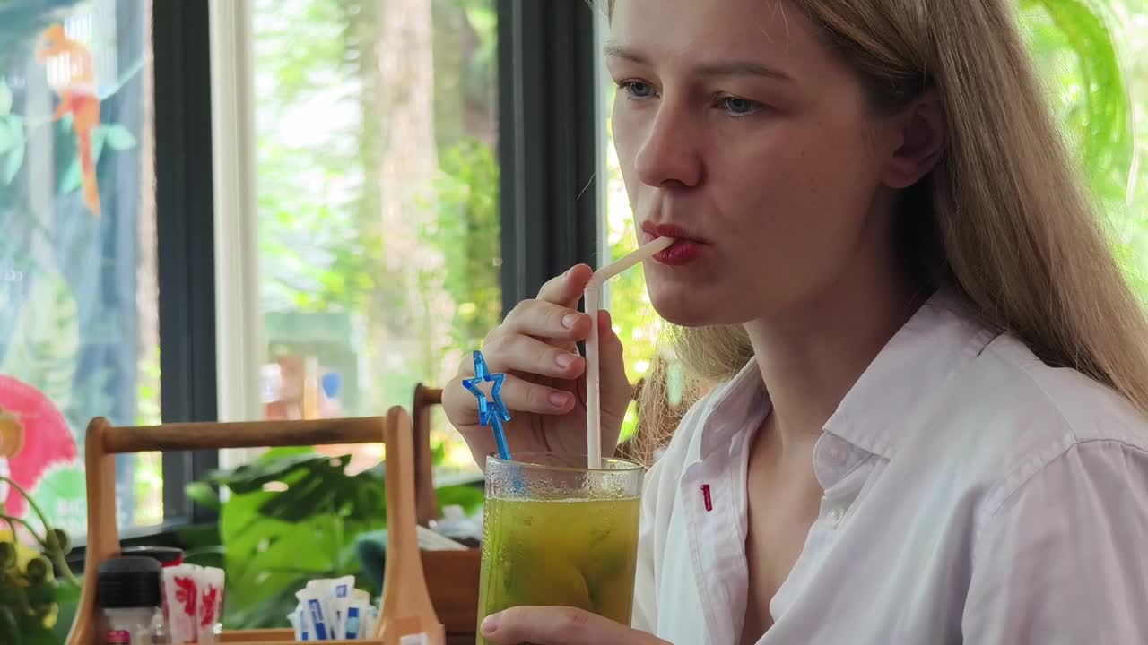 una mujer bebiendo jugo en un café.