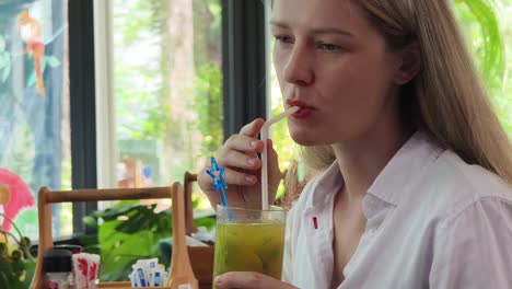 una mujer bebiendo jugo en un café.