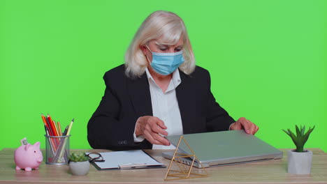 sad unhappy senior office businesswoman putting on face medical mask, prevent respiratory infection