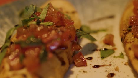 close-up of hand picking up bruschetta from plate, shallow depth, warm ambient lighting