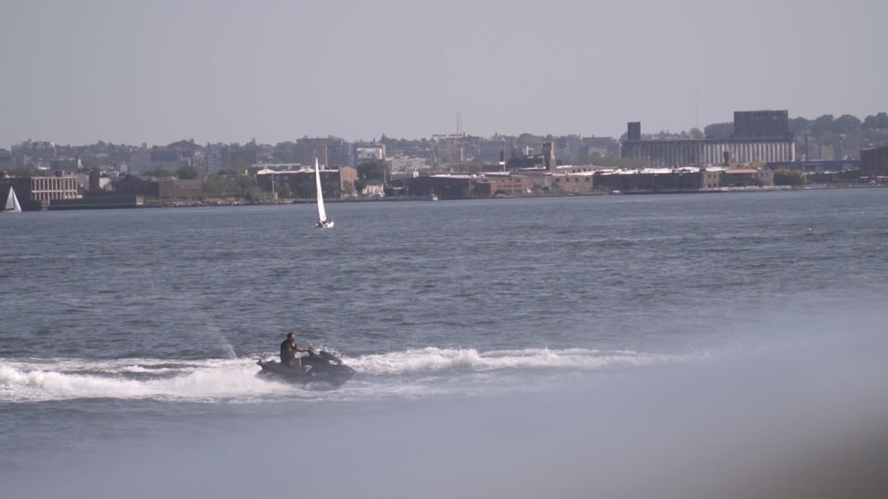 Man riding Jet Ski on the Hudson River in slow motion during sunny day in New York City, USA.