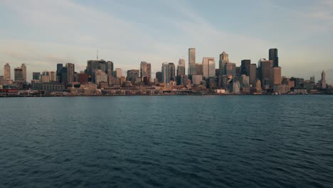 slow cinematic dolly above gentle water establishes downtown seattle waterfront skyline of buildings