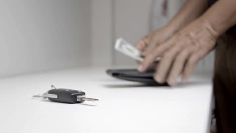 man picks up money out of the wallet on table to count