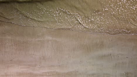 aerial drone footage of gently waves on a sandy beach