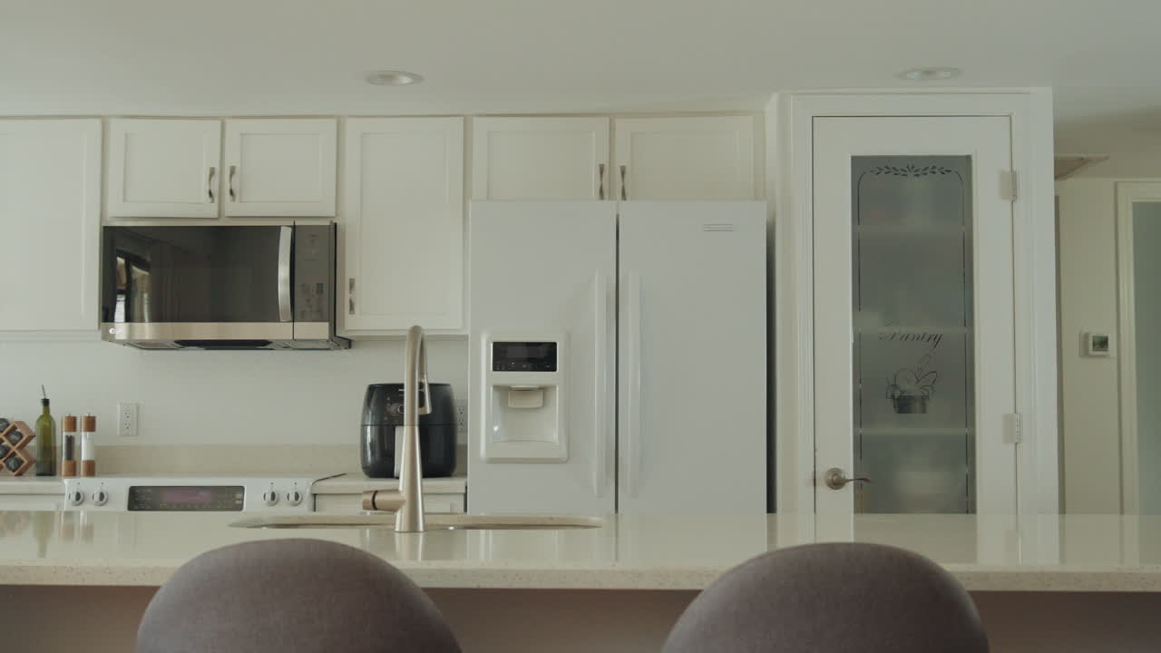 Modern kitchen with white cabinets, fridge, microwave, and a clean countertop view
