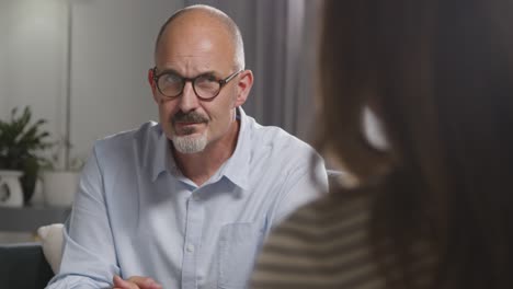 mature man sitting on sofa talking with female counsellor about general or mental health issue 6