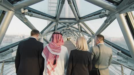 multi-ethnic business team walking along glass bridge