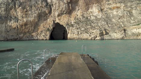 walking on stone pier near inland sea caves with mediterranean sea waves crashing from sides