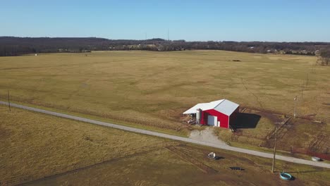 low altitude aerial view of small barn on an open field