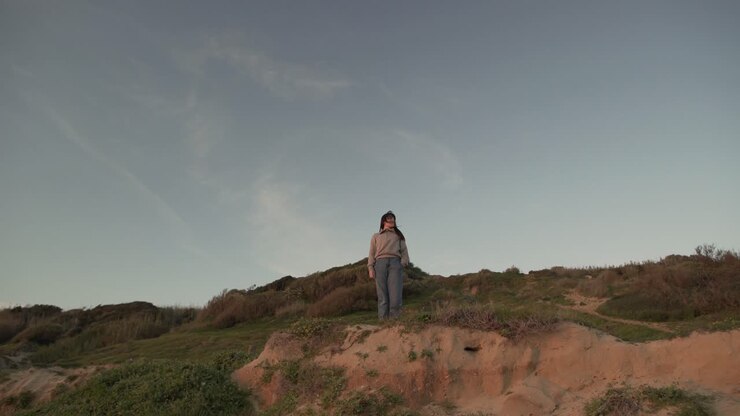 Traveling woman standing on hill at sunset
