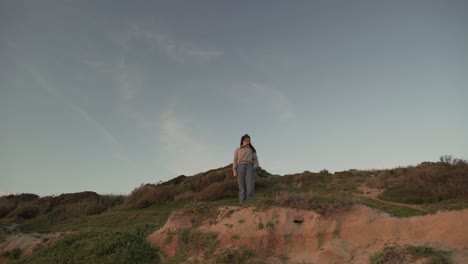 mujer viajando de pie en la colina al atardecer