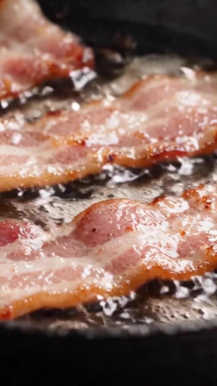 Sprød bacon på en pande: Et nærbillede af sprøde strimler, der frigiver smagfuldt fedt og aromaer under tilberedningen