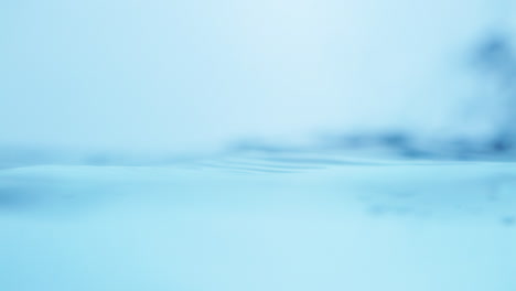 Close-up-shot-of-crystal-clear-blue-waters-bursting-into-waves,-creating-splatters-and-bubbles-in-a-big-water-tank