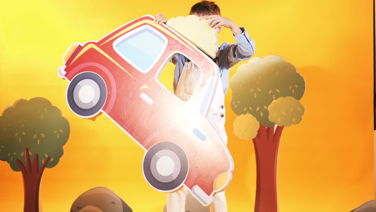 Little boy with a red car in the studio. Yellow background. Bright scenery.