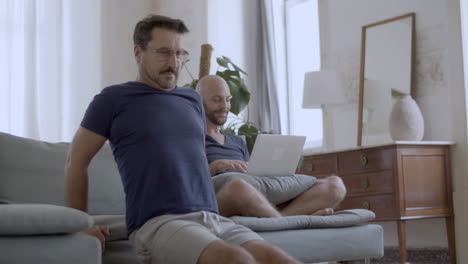 gay guapo con gafas haciendo flexiones en el sofá en casa