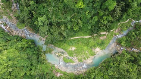 people trekking trail along creek in lush green jungle, cebu