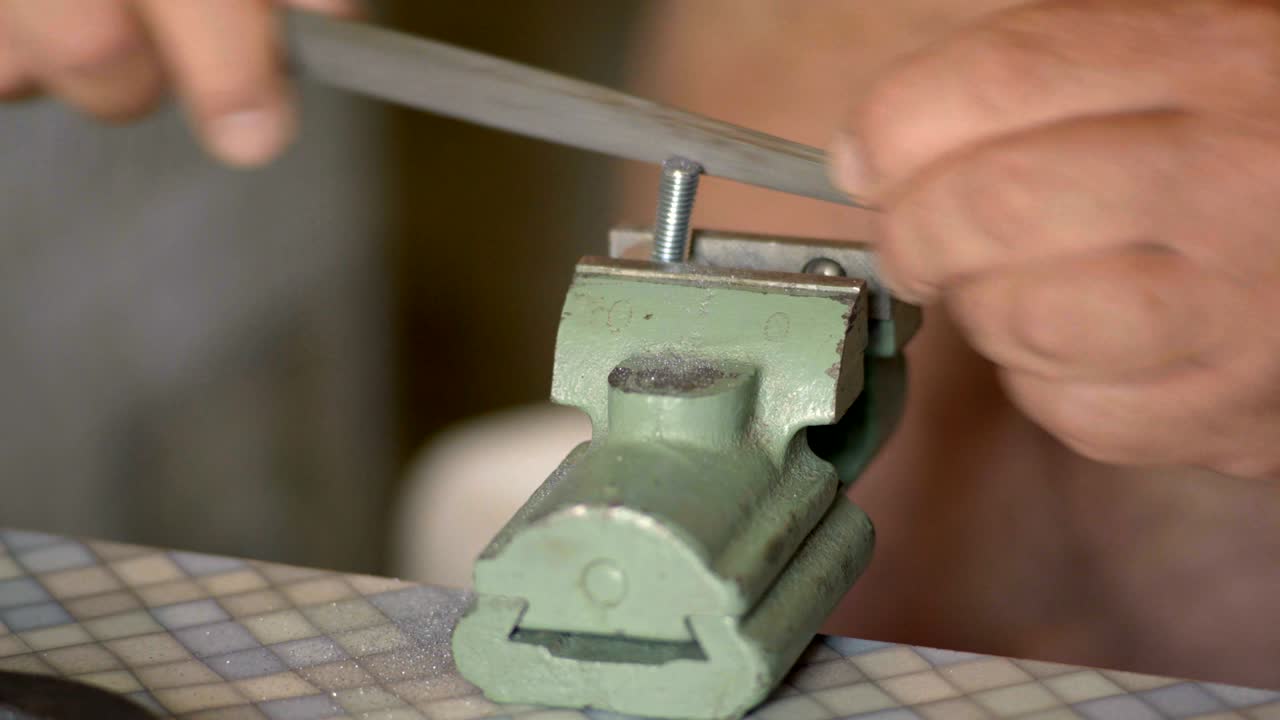 Close-up, The Old Man Handles the File Clamped in the Vise Bolt