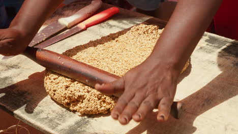 close-up of hands rolling a thick, granular dough-like mixture on a wooden board